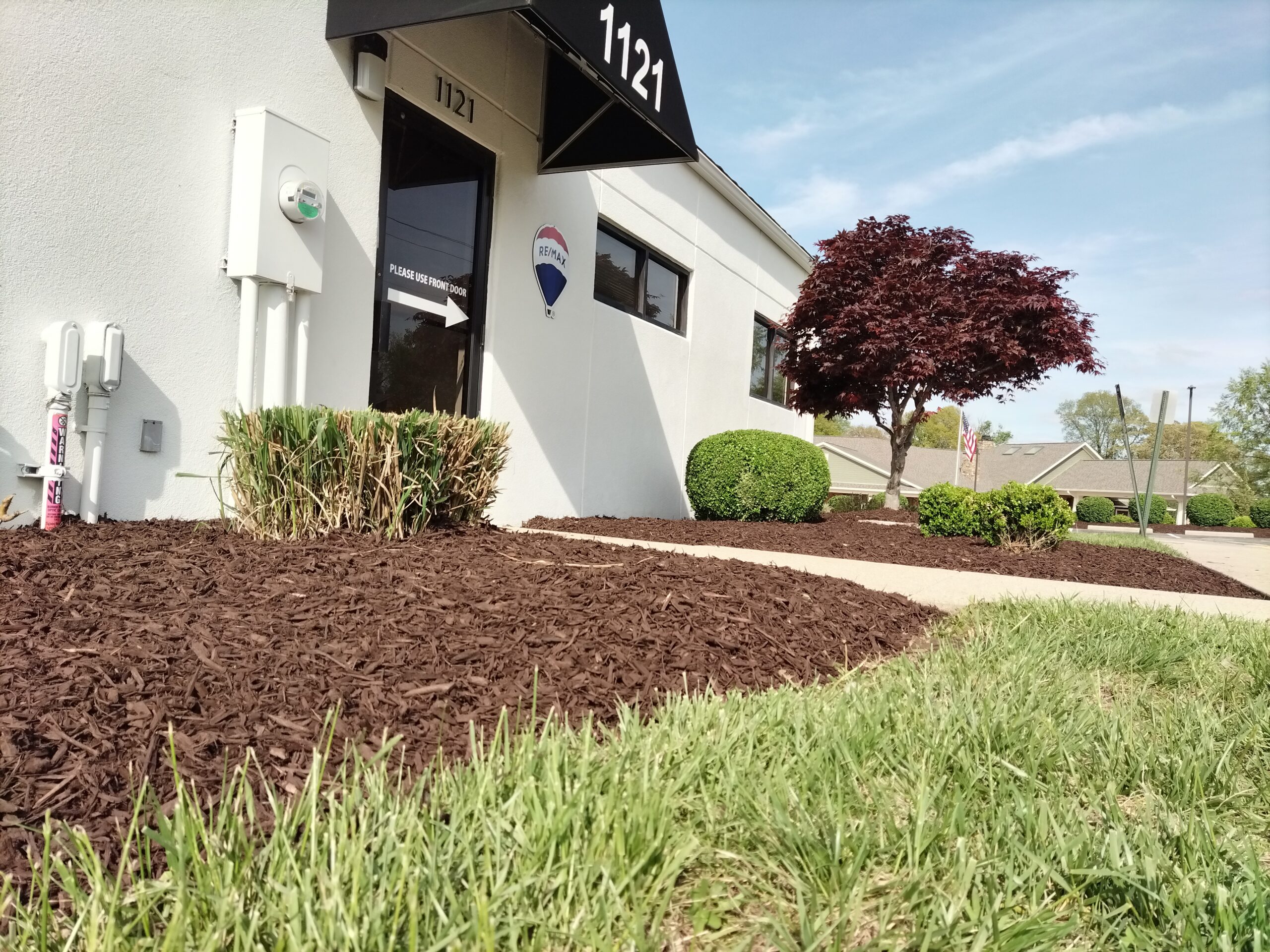 A lawn with mulch featuring a sign that reads "Real Estate," indicating property for sale or lease.